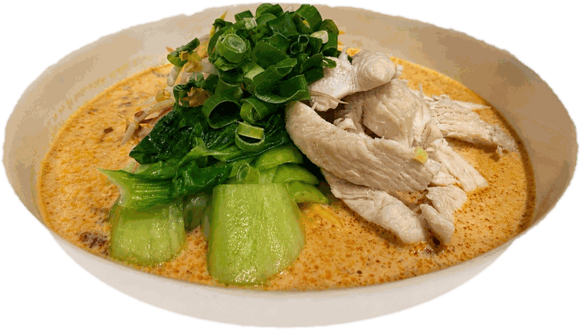 Chicken laksa with bok choy, poached chicken and spring onion, in a big white bowl